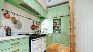 A kitchen with green cabinets, white countertops, and a wooden herringbone floor. - Charming 1 Bedroom 1 Bathroom Notting Hill (London)