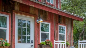 A wooden house with a white door, two windows, and a porch with white rocking chairs. - Cozy Cabin Little Red Hen 12 min to Magnolia (Waco)