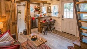 A cozy cabin interior with a dining area, kitchen, and a staircase. - Cozy Cabin Little Red Hen 12 min to Magnolia (Waco)