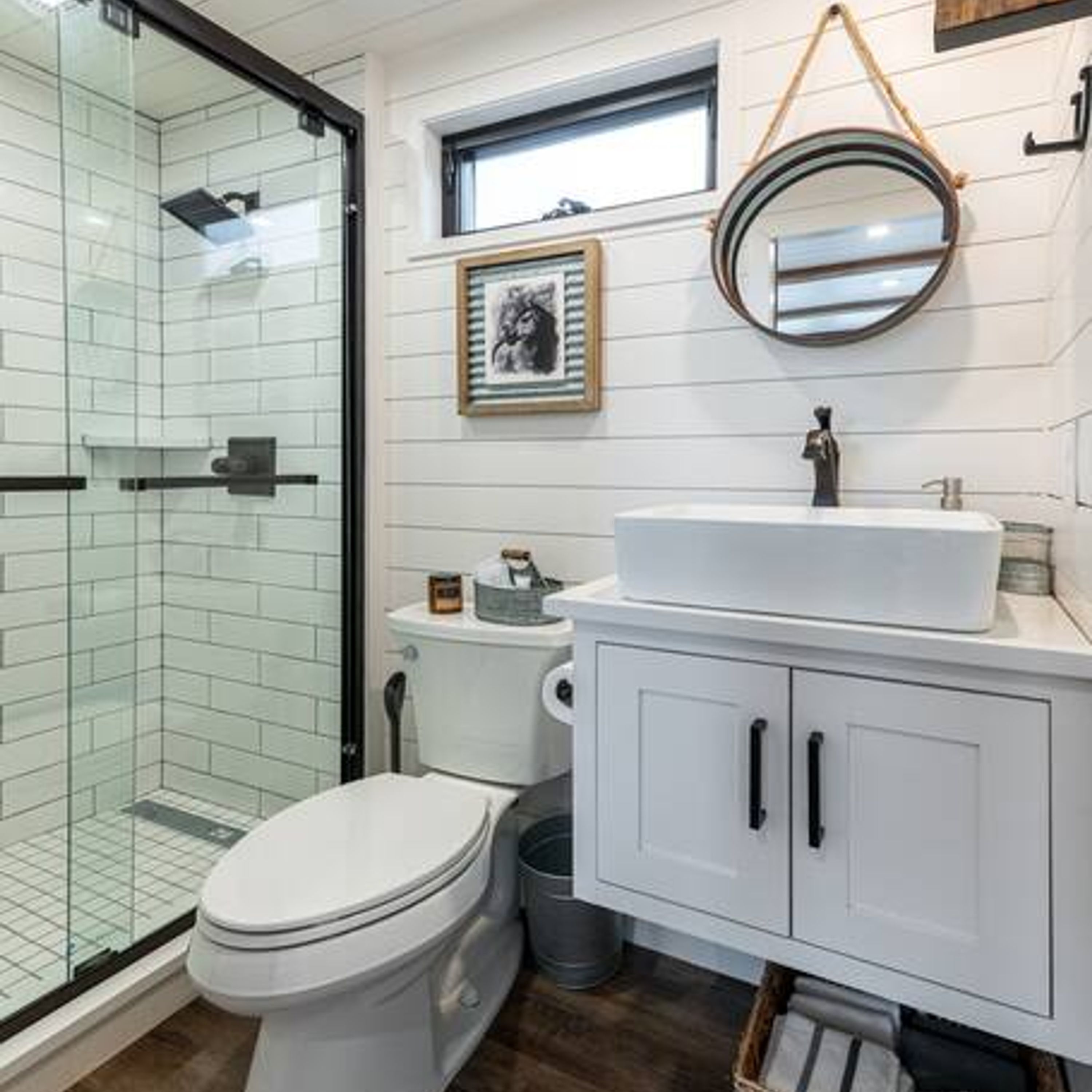 Ein Badezimmer mit Duschkabine aus Glas, Toilette, Waschbecken und Spiegel.