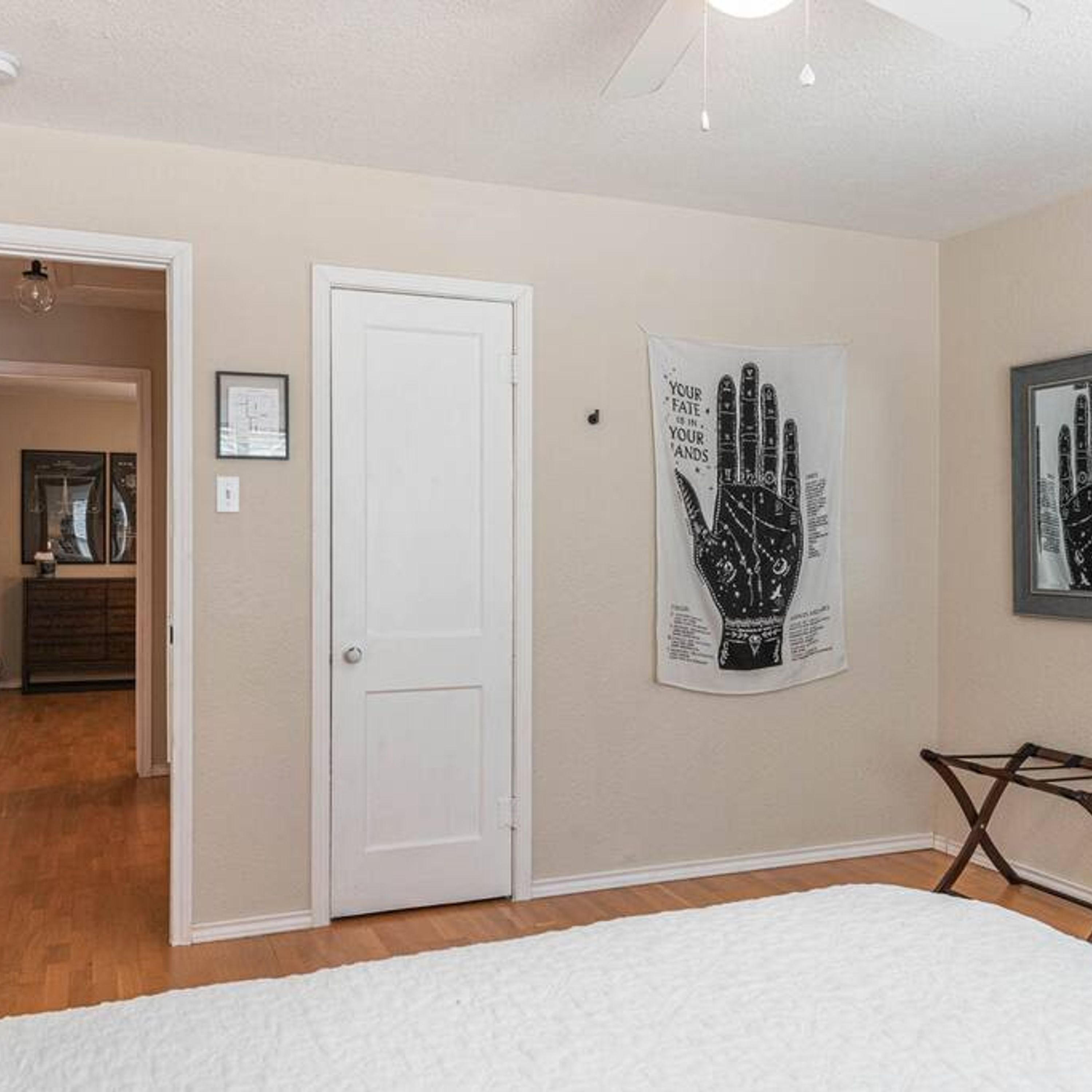 A bedroom with a white door, a handprint artwork, and a bed.