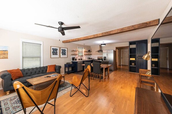 Relax in this open-plan living space with a kitchen area, featuring a sofa, coffee table, dining table, and bookshelves.