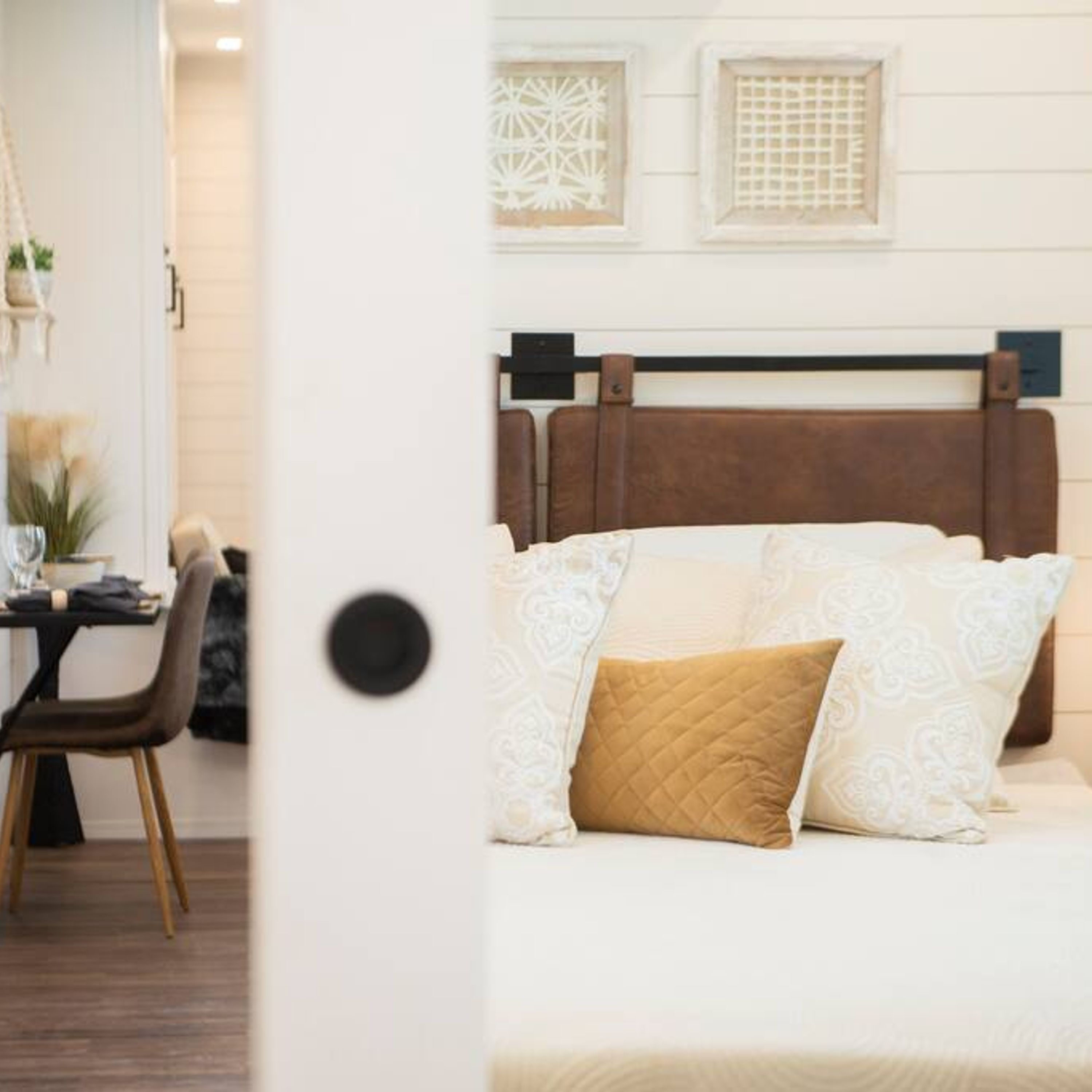Une chambre à coucher avec une tête de lit en bois, un lit agrémenté d’oreillers à motifs et un climatiseur fixé au mur.