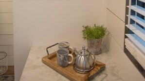 Eine Küche mit Holzböden, die weiße Schüsseln und Tassen, eine kleine Pflanze sowie ein Tablett mit Teekanne und Tassen beherbergt.