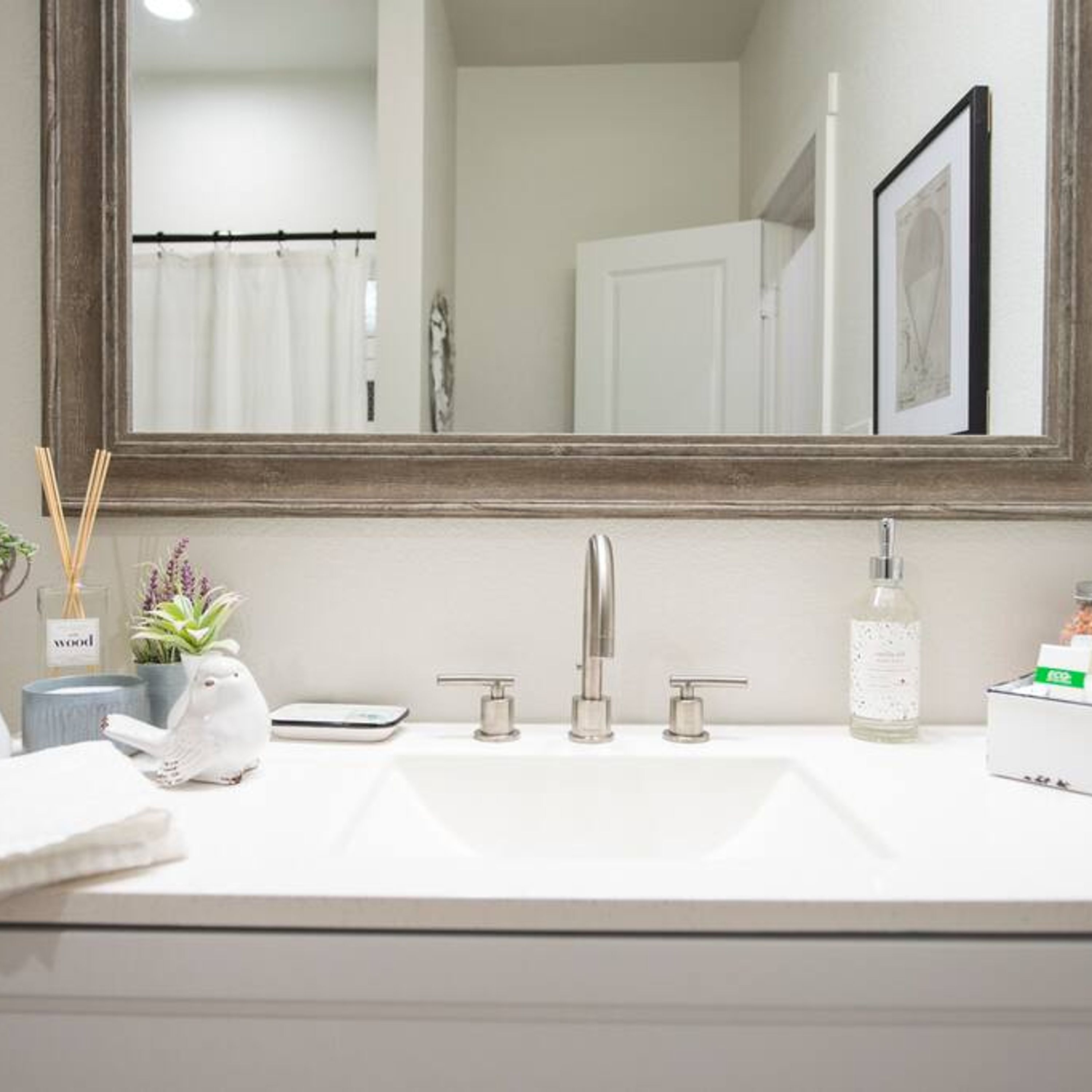 A bathroom with a white sink, two faucets, a mirror, and a towel rack.