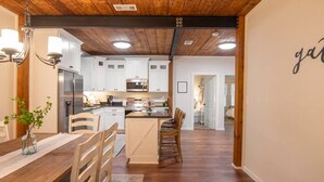 Une cuisine spacieuse avec des meubles de rangement en bois, un coin repas avec une table et des chaises en bois, et un couloir menant aux autres pièces.
