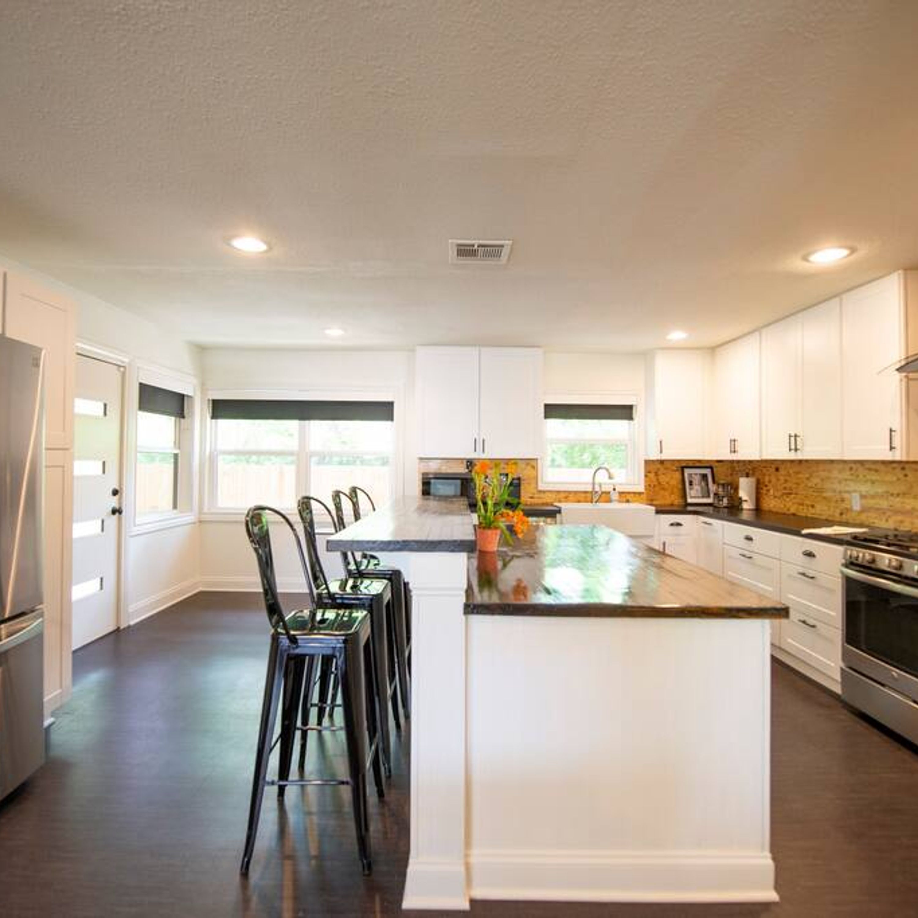 Una cocina moderna con armarios blancos, una isla central y un refrigerador de acero inoxidable.