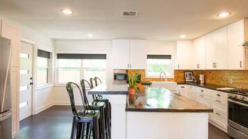 Una cocina moderna con armarios blancos, una isla central y un refrigerador de acero inoxidable.