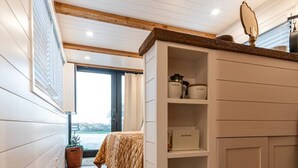 A bedroom with a bed, a dresser, and a window. - Deer Creek Tiny Container Home-12 Min to Magnolia (Waco)