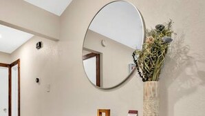 A hallway with a wooden console table, a round mirror, and a vase with flowers.