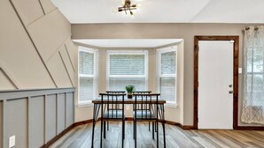 A dining area with a bay window, a ceiling fan, and a door with a curtain.