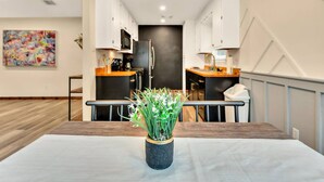 A modern kitchen with white cabinets, a black refrigerator, and a wooden countertop.