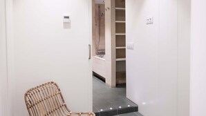 Een moderne badkamer met een douche, een stoel en een spiegel.