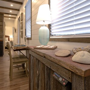 A wooden reception desk with a lamp, a remote control, and decorative items. - The Shoreline Container Tiny Home 12 min to Magnolia Baylor (Waco)
