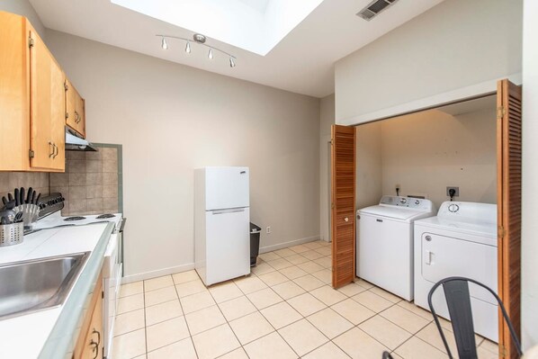 A compact kitchen with a gas stove, white refrigerator, and built-in oven. - New Gathering Place on Columbus (Waco)