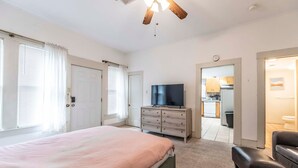 A bedroom with a bed, a TV, a dresser, and a ceiling fan. - New Gathering Place on Columbus (Waco)