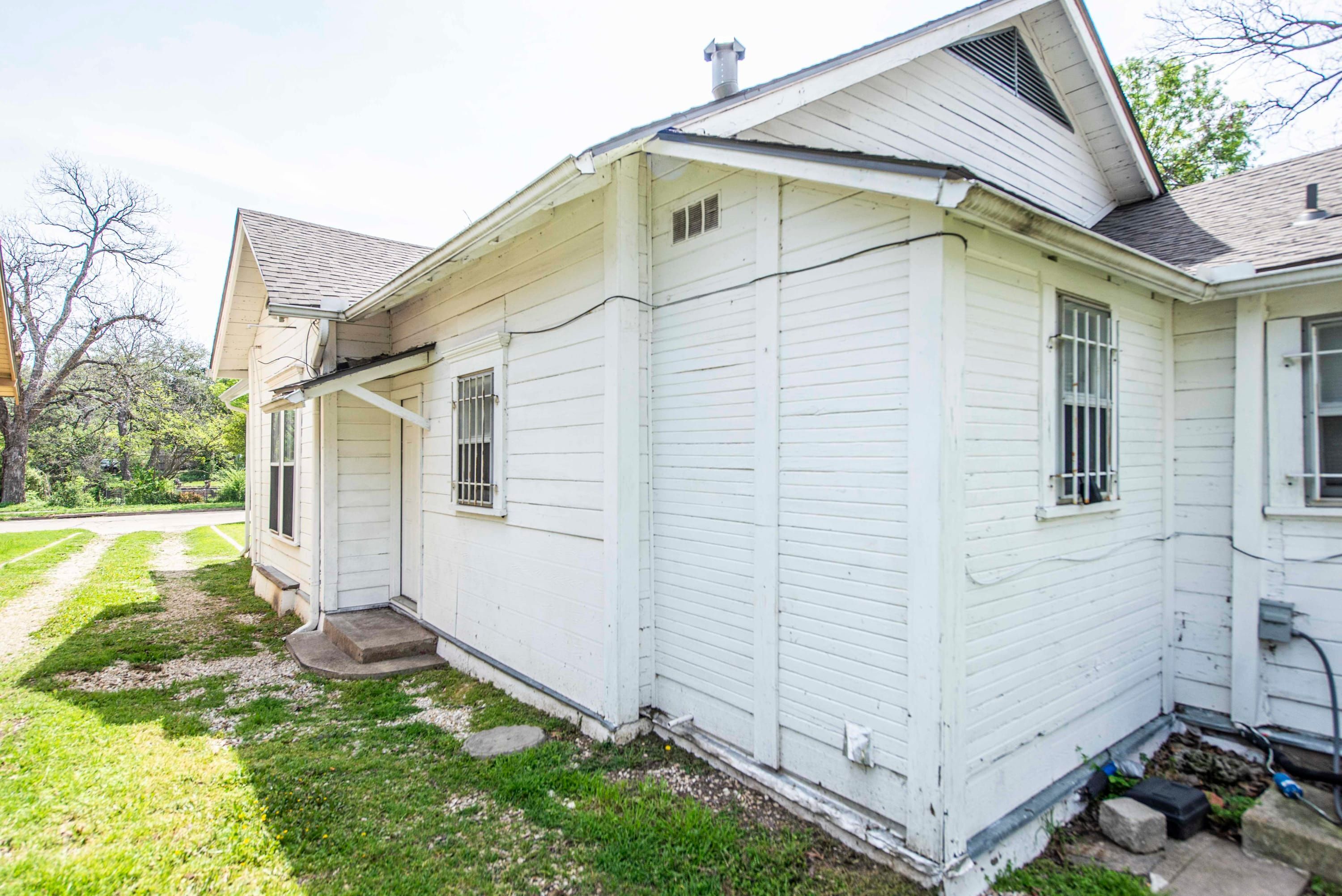 A white single-story house with a front porch, a small front yard, and a garage.