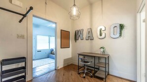 A hallway with a desk, a chair, and a wall-mounted sign spelling "WACO". - New Gathering Place on Columbus (Waco)
