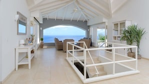 A spacious living area with a view of the sea, a balcony with a white railing, and a dining area with a white cabinet. - Shoreline Harmony at Villa Solana (Sint Willibrordus)