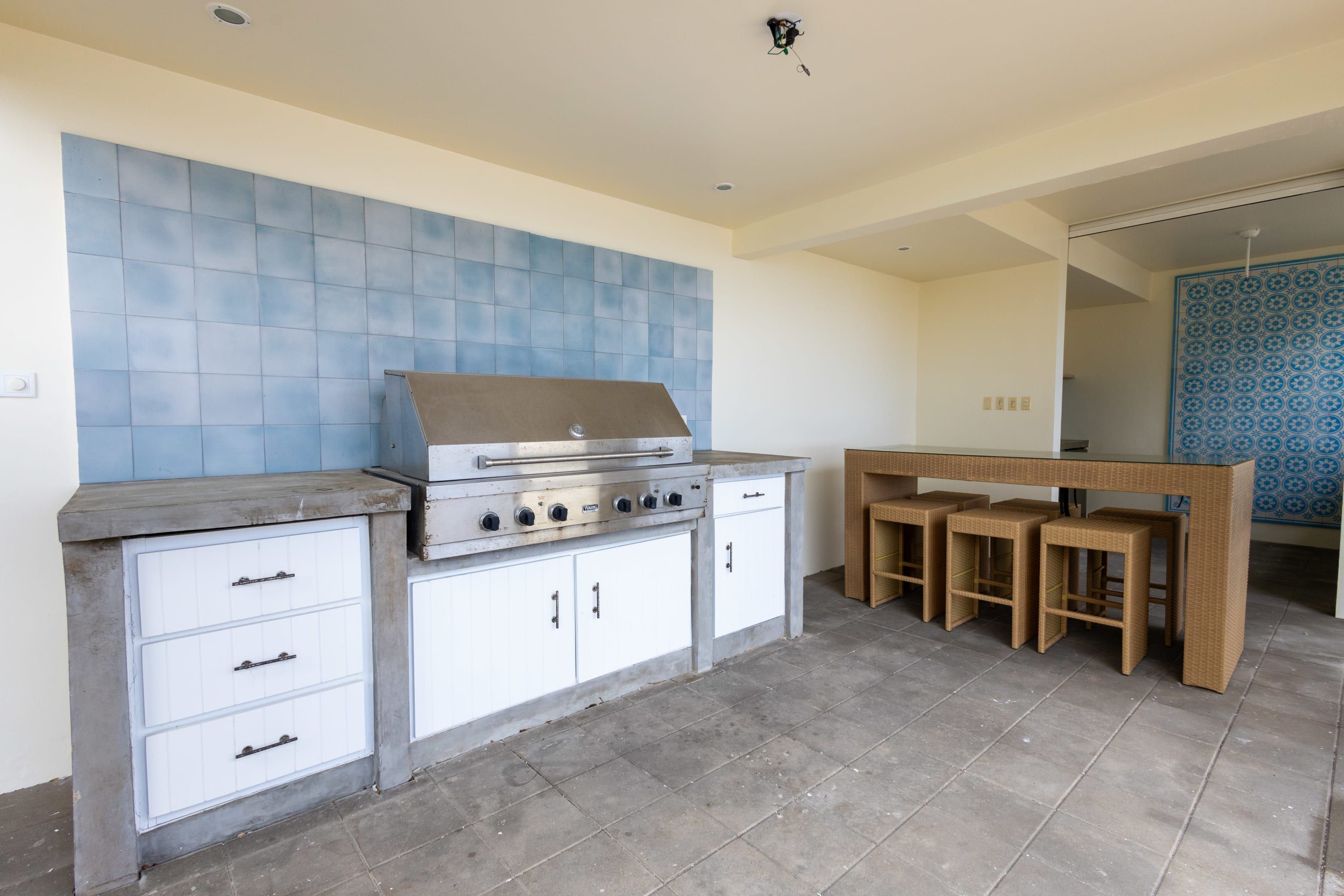 A kitchen with a built-in gas stove, white cabinets, and a blue tiled backsplash.