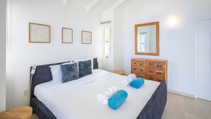 A hotel room with a large bed, a wooden dresser, and a mirror on the wall. - Shoreline Harmony at Villa Solana (Sint Willibrordus)