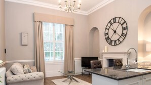 A spacious living room with a large window, a fireplace, a dining area, and a kitchen with a large island. - The Barrington (Durham)