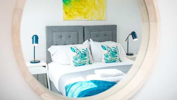 Ein Schlafzimmer mit Bett, Nachttisch, Lampe und einem Gemälde an der Wand.