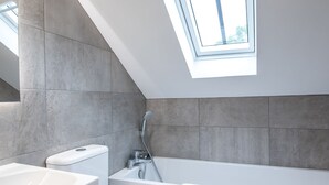 Ein modernes Badezimmer mit Oberlicht, Badewanne und Toilette.