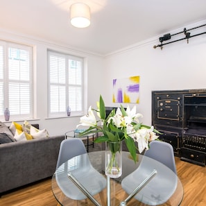 Una sala de estar moderna con una mesa de vidrio, un sofá gris y un jarrón con flores blancas.