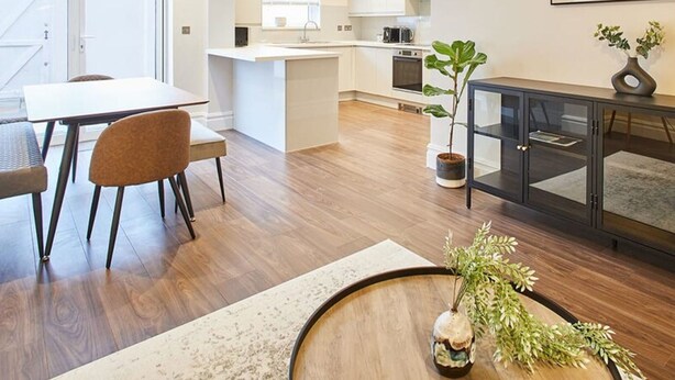 A modern kitchen with white cabinets, a central island, and a dining area with a table and chairs. - Host Stay Belle Vue (Saltburn-by-the-Sea)