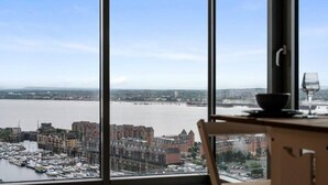 A view from a high-rise window overlooking a river, with buildings and a bridge in the distance. - Host Apartments Kings Dock View Baltic Living (Liverpool)
