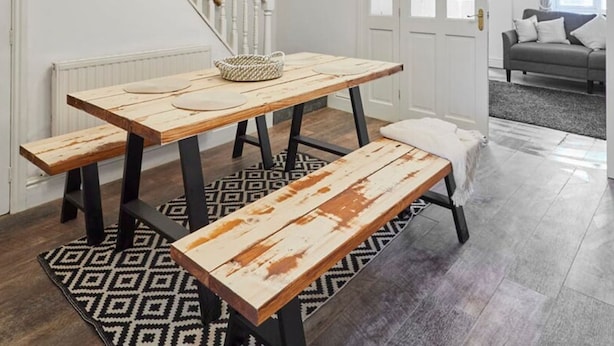 A dining area with a wooden table and benches, a patterned rug, and a staircase. - Host Stay Church Street (Warrington)