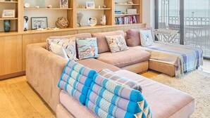 Ein modernes Wohnzimmer mit einer Eckcouch, integrierten Regalen und Meerblick durch große Fenster.