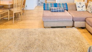 Ein gemütliches Wohnzimmer mit einer Couch, einem Esstisch mit Stühlen, einer Treppe und einem Bild an der Wand.