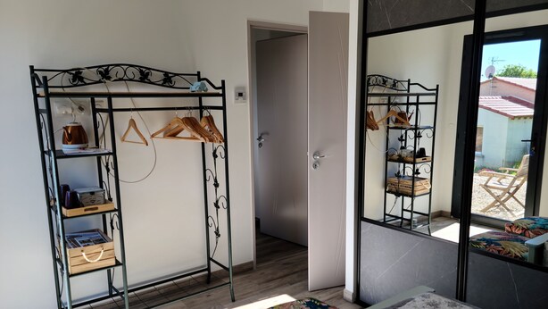 Une pièce avec une armoire en métal, un lit recouvert d’une couvre-lit à motifs et une vue sur l’extérieur par une porte vitrée.