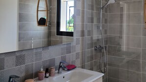 Une salle de bain moderne avec un grand miroir, deux lavabos, une douche et des carreaux décoratifs.