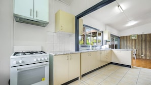 A kitchen with white cabinets, a gas stove, and a window providing natural light. - Metawise/parramatta Cozy Room With Furniture Wifi (Parramatta)