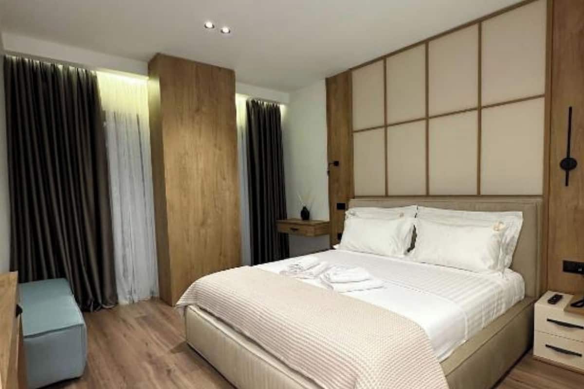 Un dormitorio moderno con una cama grande, suelo de madera y cabecero incorporado.