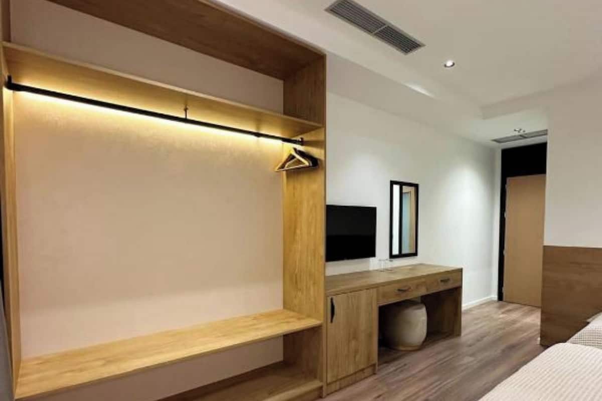 Un dormitorio moderno con estructura de cama de madera, una mesita de noche y un banco empotrado con lámpara colgante.
