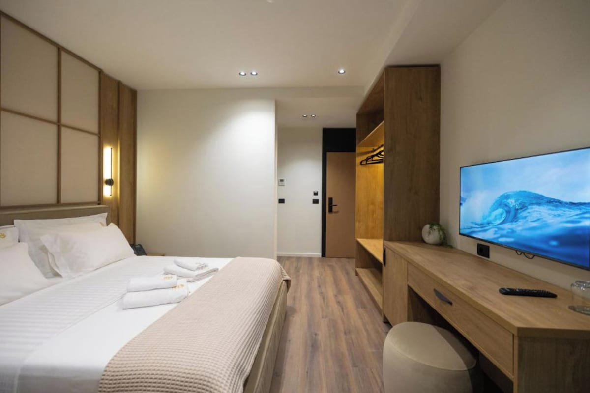 A hotel room with a bed, a TV, a desk, and a wardrobe.