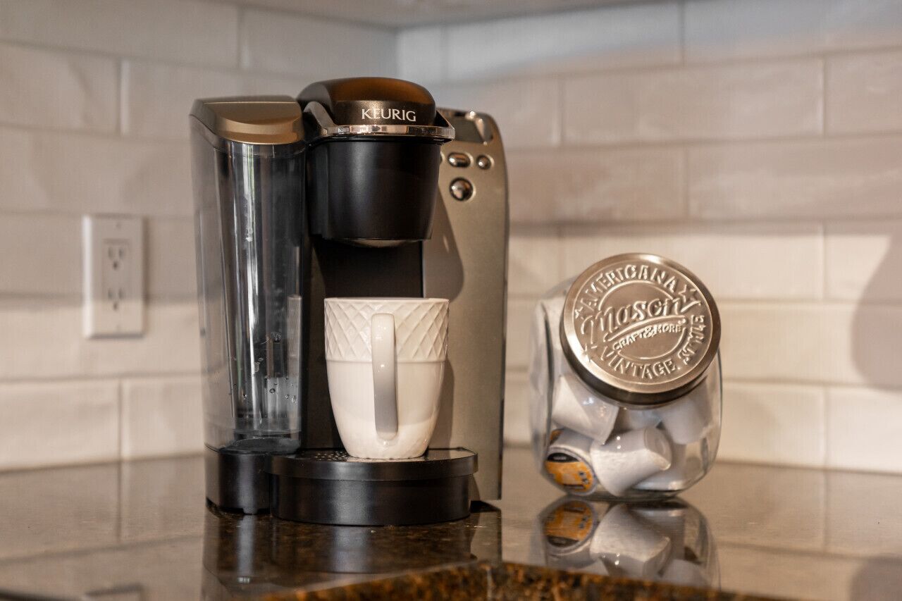 A coffee maker with a white mug on a kitchen counter.