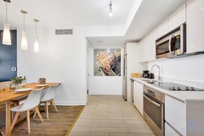 A modern kitchen with white cabinetry, stainless steel appliances, and pendant lighting. - Spectacular Balcony Near Beach Gym Pool (Hallandale Beach)