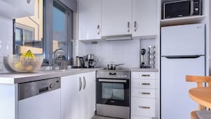 A modern kitchen with white cabinets, stainless steel appliances, and a window providing natural light. - Aqua Villa II - Entire villa in Elafonisos, Laconia, Greece (Peloponnese)