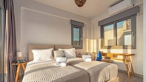 A double bed with two pillows, a bedside table with a lamp, and a window with curtains. - Aqua Villa II - Entire villa in Elafonisos, Laconia, Greece (Peloponnese)