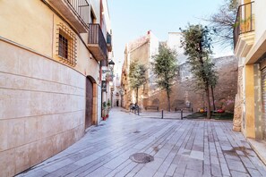 A narrow street with buildings on either side, a paved walkway, and trees. - Unik Vacation Ripoll (Tarragona)