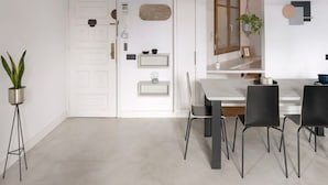 Un espace repas moderne avec une table blanche, des chaises noires et un plafond en bois.