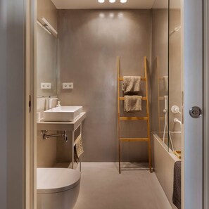 A compact bathroom with a toilet, sink, and shower. A wooden ladder with towels is placed against the wall. - Blue Velvet Premium 2BR Near Plaza Catalunya (Barcelona)