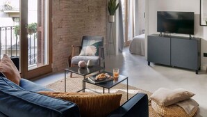 Un salon moderne avec un canapé, une table basse, un téléviseur et un meuble gris.