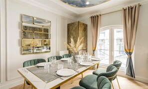 A dining room with a marble table, green upholstered chairs, and a gold-framed mirror. - CHIC PARISIAN RETREAT: LUXURY 3-BEDROOM APARTMENT NEAR LOUVRE AND LE MARAIS (Paris)