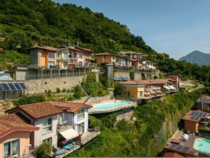 A hillside residential area with multiple houses, a swimming pool, and solar panels. - Panorama in Spiglia With 1 Bedrooms and 1 Bathrooms (Parzanica)
